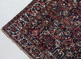 Antique Persian area rug in a living room setting, pile rug, vintage rug, portland, rug shop, bright colors, wild shaman, soft rug, bold color, Portland, Oregon, rug store, rug shop, local shop, antique rug, Persian rug, handmade rug, wool rug, distressed rug