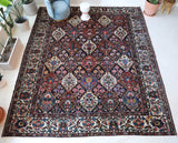 Antique Persian area rug in a living room setting, pile rug, vintage rug, portland, rug shop, bright colors, wild shaman, soft rug, bold color, Portland, Oregon, rug store, rug shop, local shop, antique rug, Persian rug, handmade rug, wool rug, distressed rug
