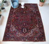 Antique Persian area rug in a living room setting, pile rug, vintage rug, portland, rug shop, bright colors, wild shaman, soft rug, bold color, Portland, Oregon, rug store, rug shop, local shop, antique rug, Persian rug, handmade rug, wool rug