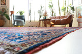 Antique Persian area rug in a living room setting, pile rug, vintage rug, portland, rug shop, bright colors, wild shaman, soft rug, bold color, Portland, Oregon, rug store, rug shop, local shop, antique rug, Persian rug, handmade rug, wool rug, distressed rug