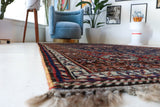Antique Persian  rug in a living room setting, pile rug, vintage rug, portland, rug shop, bright colors, wild shaman, soft rug, bold color, Portland, Oregon, rug store, rug shop, local shop, antique rug, Persian rug, handmade rug, wool rug, distressed rug