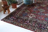 Antique Persian area rug in a living room setting, pile rug, vintage rug, portland, rug shop, bright colors, wild shaman, soft rug, bold color, Portland, Oregon, rug store, rug shop, local shop, antique rug, Persian rug, handmade rug, wool rug, distressed rug