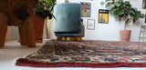 Antique Persian area rug in a living room setting, pile rug, vintage rug, portland, rug shop, bright colors, wild shaman, soft rug, bold color, Portland, Oregon, rug store, rug shop, local shop, antique rug, Persian rug, handmade rug, wool rug, distressed rug