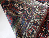 Antique Persian area rug in a living room setting, pile rug, vintage rug, portland, rug shop, bright colors, wild shaman, soft rug, bold color, Portland, Oregon, rug store, rug shop, local shop, antique rug, Persian rug, handmade rug, wool rug, distressed rug