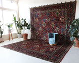 Antique Persian area rug in a living room setting, pile rug, vintage rug, portland, rug shop, bright colors, wild shaman, soft rug, bold color, Portland, Oregon, rug store, rug shop, local shop, antique rug, Persian rug, handmade rug, wool rug, distressed rug