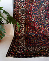 Antique Persian area rug in a living room setting, pile rug, vintage rug, portland, rug shop, bright colors, wild shaman, soft rug, bold color, Portland, Oregon, rug store, rug shop, local shop, antique rug, Persian rug, handmade rug, wool rug